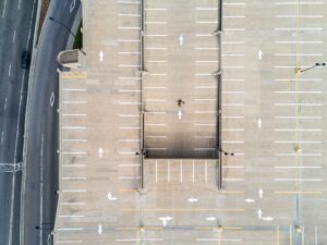 Person lying on gray concrete parking area in aerial photography