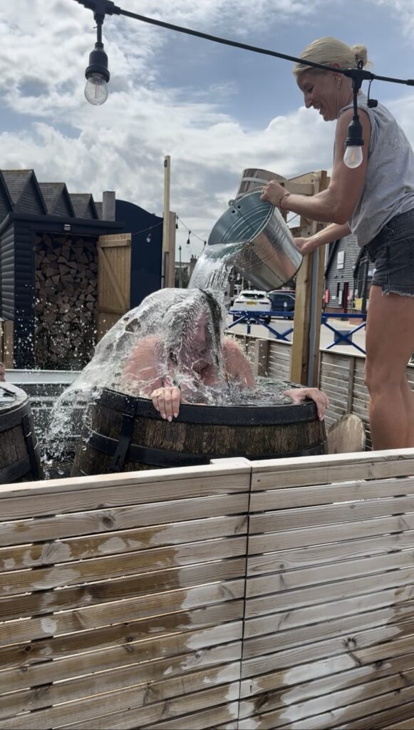 Numi getting water thrown on her head, in a plunge barrel